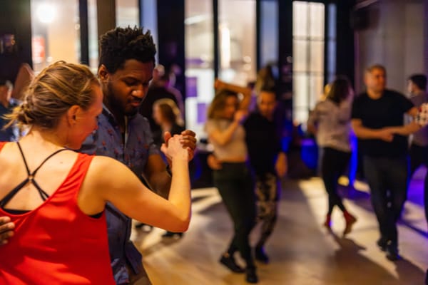 two people dancing with other dancers in background